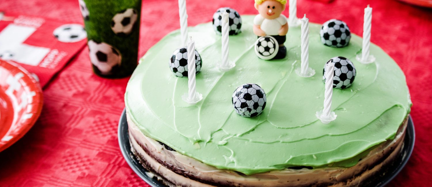 Kids birthday party Football theme. Chocolate cake decorated like football field with seven candles.